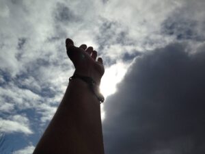 photo of hand raised to a cloudy sky